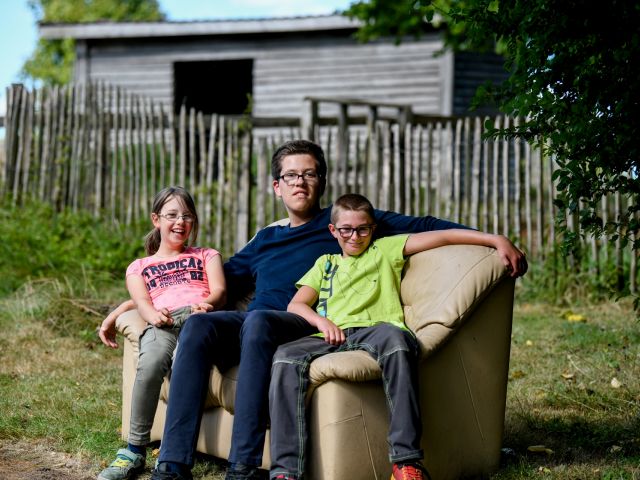 3 Kinder sitzen auf einem Sofa im Garten